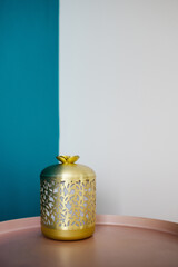 Oil diffuser on the pink table in the minimalistic interior with turquoise and white wall. Golden diffuser. Minimalistic interior.