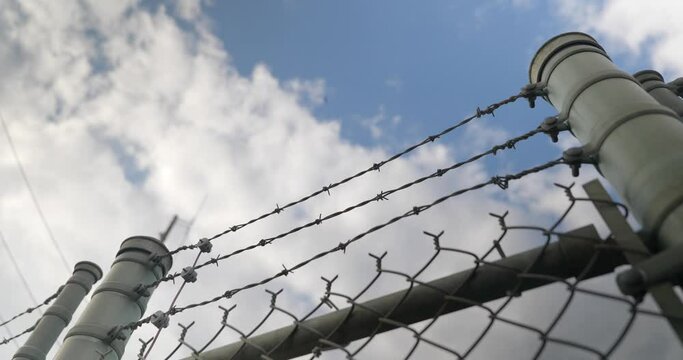 Top of chain link fence barbed wire blue sky clouds