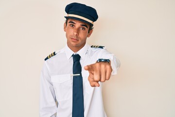 Young hispanic man wearing airplane pilot uniform pointing displeased and frustrated to the camera, angry and furious with you