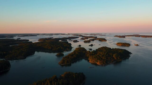 Aerial view above islands, during sunrise, in the Finland-Russia border archipelago - tracking, drone shot