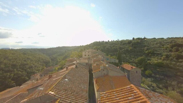Old typical Italian village, nestled in the green hills of Tuscany. In the middle of the narrow alleys of the houses, fpv drone.