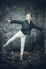 Fototapeta na wymiar Young dancer dressed in white jeans and blue shirt doing figures studio portrait