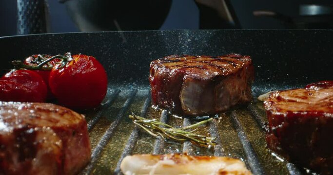 Chef preparing a delicious meal. Cooker frying pieces of juicy beef meat and tasty vegetables on grill. Steak grilled on professional kitchen - food art, food and drink 4k footage
