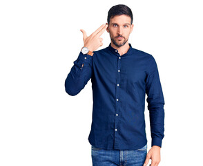 Young handsome man wearing casual shirt shooting and killing oneself pointing hand and fingers to head like gun, suicide gesture.