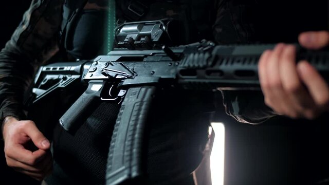 Military man brings his weapon into a combat position. Black background