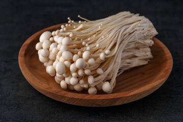 Enoki mushrooms over black background .Enokitake or enoki (Flammulina velutipes) white mushroom used i food and salads, also known by the name golden needle mushroom or lily mushroom.