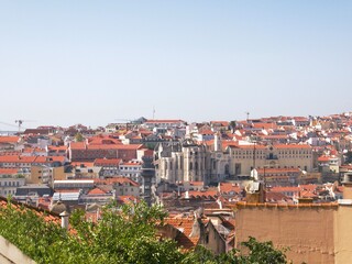 Fototapeta na wymiar Lisbon city scape with buildings with red roofs and a cathedral on a hot summer day