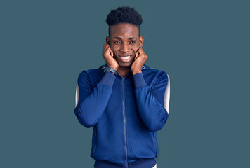 Young african american man wearing sportswear covering ears with fingers with annoyed expression for the noise of loud music. deaf concept.