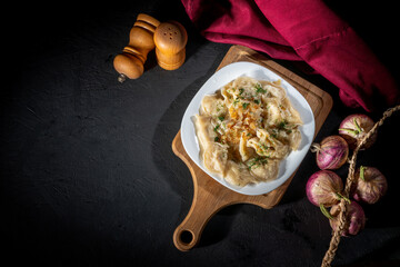Dumplings, filled with meat on dark background. Varenyky, vareniki, pierogi, pyrohy - dumplings with filling
