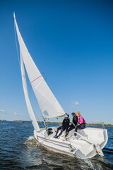 A beautiful picture with a sports yacht on the background of an urban landscape floating under full sails on a wide river