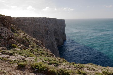 Fototapeta na wymiar Steep cliffs into azure Atlantic Ocean in Portugal Sagres