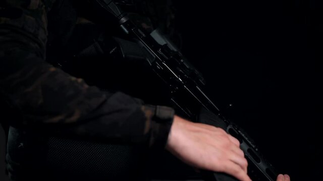 Man in a multicam on a black background unfastens an empty magazine from his machine gun