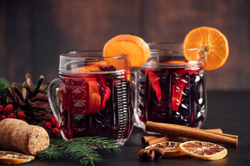 Traditional Christmas hot mulled wine. Hot drink with spices in glass cup on dark background.