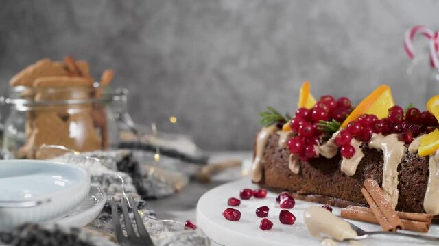 Christmas home made cinnamon cake with fruits and spekulatius cookies cream on a kitchen countertop.