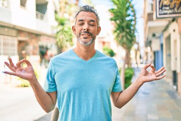 Middle age grey-haired man wearing casual clothes at street of city relax and smiling with eyes closed doing meditation gesture with fingers. yoga concept.