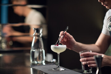 Close-up of the process of preparing a cocktail with liqueur at a party of friends in a nightclub. The dark blurred background