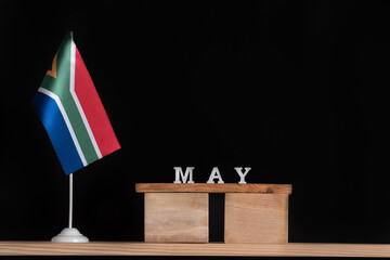Naklejka premium Wooden calendar of May with RSA flag on black background. Dates of South Africa in May.