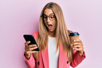 Young blonde woman using smartphone and drinking a cup of coffee celebrating crazy and amazed for...