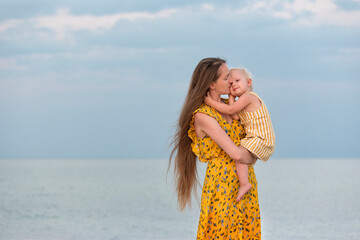 Happy beautiful mother huges baby near the sea. Mother and daughter.