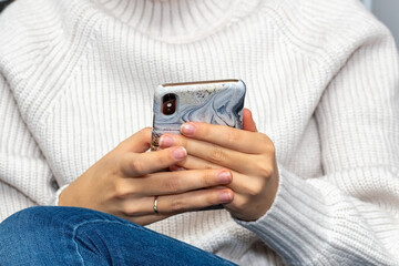 The girl holds a smartphone in her hands. Close-up.