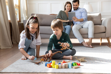 Small brother and sister kids children it on floor in living room play toys together. Happy young...