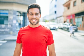 Young handsome hispanic man smiling happy. Standing with smile on face walking at town street.