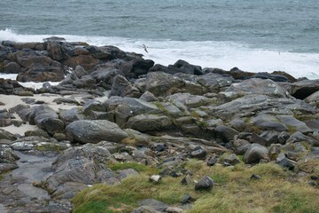Fototapeta na wymiar Angry ocean waves crushing against stone Scottish shore on a very windy day on the Isle of Barra