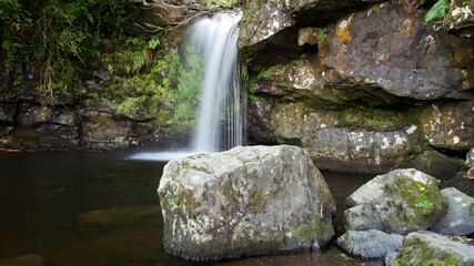 Fototapeta na wymiar Small Scottish waterfall with a big boulder in the Campsie Fells