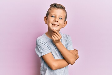 Adorable caucasian kid wearing casual clothes smiling looking confident at the camera with crossed arms and hand on chin. thinking positive.