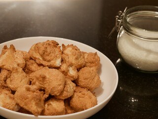 Soft golden coconut cookies piled on a plate next to a mason jar filled with coconut