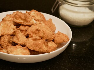 Soft golden coconut cookies piled on a plate next to a mason jar filled with coconut
