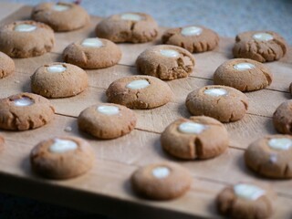 many small round freshly baked ginger, honey and cinnamon cookies with a creamy eye assorted on a chopping board