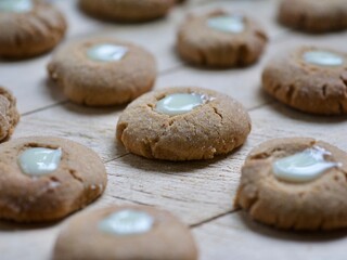 many small round freshly baked ginger, honey and cinnamon cookies with a creamy eye assorted on a chopping board