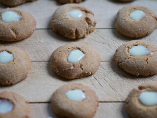 many small round freshly baked ginger, honey and cinnamon cookies with a creamy eye assorted on a chopping board