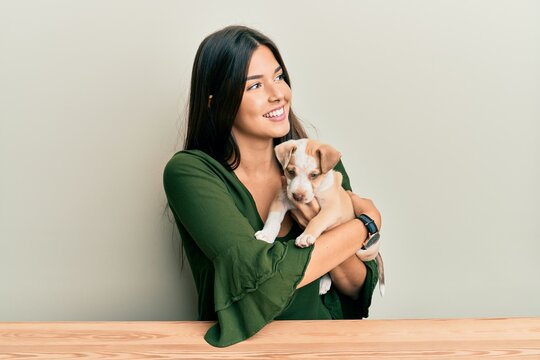 Young hispanic girl smiling happy and hugging dog sitting on the table over isolated white background.