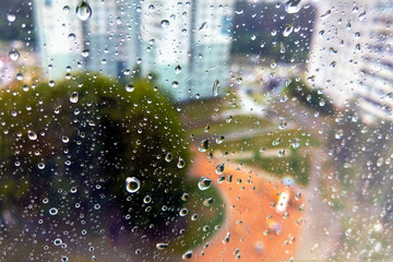 Window with large drops of rain on a gray urban background. The first summer storm, close-up. rain drops on the window glass large detailed, selective focus.