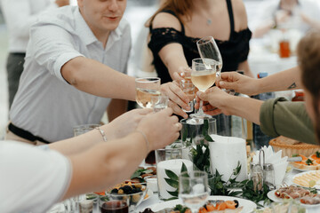 Faceless people clinking the champagne glasses at the wedding. Party in the restaurant