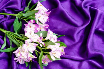 Lily flower bouquet on smooth elegant purple natural silk luxury fabric texture