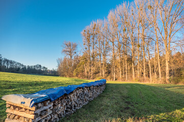 Mit einer Abdeck Plane geschützter Brennholz Stapel © focus finder