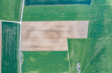 Top down aerial view from a drone on French farmland landscape with agricultural fields, roads and small house