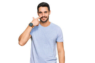 Young hispanic man wearing casual clothes pointing with hand finger to face and nose, smiling cheerful. beauty concept