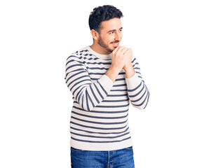 Young hispanic man wearing casual clothes laughing nervous and excited with hands on chin looking to the side