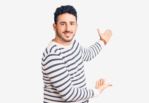 Young hispanic man wearing casual clothes inviting to enter smiling natural with open hand