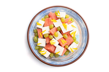 Vegetarian salad with watermelon, feta cheese, and grapes on blue ceramic plate isolated on white background. top view