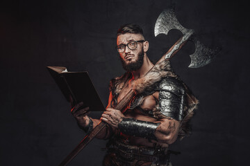 Holding two handed axe on his shoulder nordic fighter weared with glasses poses in dark background...
