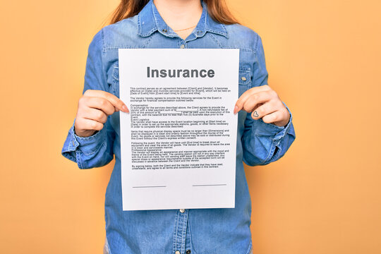 Woman holding insurance document paper standing over isolated yellow background
