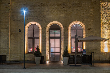 Facade of an old 18th century brick building with arched doors and windows in the evening.