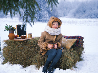 Winter picnic in nature. Cute child with a mug of hot tea