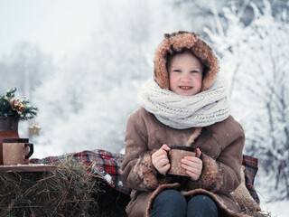 Winter picnic in nature. Cute child with a mug of hot tea