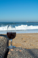 Tasting of different fortified dessert ruby, tawny port wines in glasses on sandy beach with view on waves of Atlantic ocean near Vila Nova de Gaia and city of Porto, Portugal